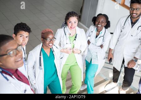 Junge Ärzte, gemischten Rennen, Sitzen, Stehen auf der Treppe, im Flur des Krankenhauses. Sie betrachten x-Strahlen, die Verwendung von Minianwendungen in der Medizin zu arbeiten. Peo Stockfoto