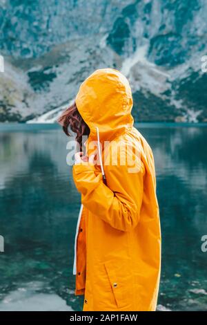 Frau im gelben Regenmantel am See Strand im Nationalpark Tatra Stockfoto