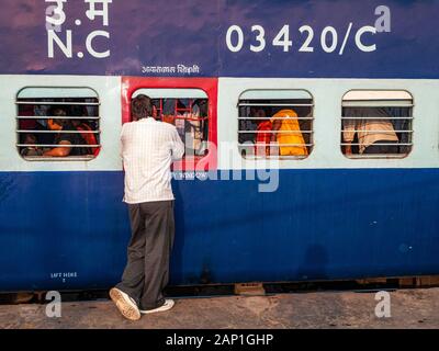 Ein Mann, der mit Leuten im Zug spricht, bevor er den Bahnhof von Neu-Delhi verlässt Stockfoto