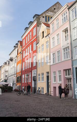 Kopenhagen, Dänemark - Dezember 9, 2017: alte Häuser in einer Reihe, traditionellen architektonischen Stil von Kopenhagen, gewöhnliche Menschen gehen auf die Straße. Vertikale Stockfoto