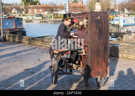 Straßenmusiker oder Busker, der auf einem Fahrrad ein Klavier spielt und in Stratford-upon-Avon, Warwickshire, Großbritannien, spielt Stockfoto