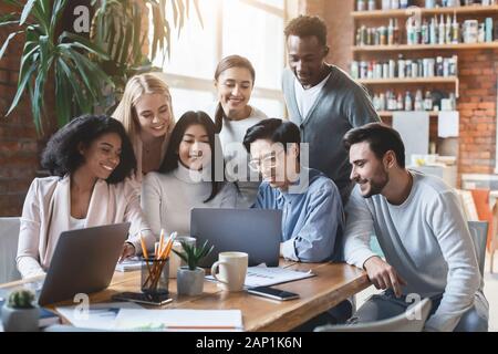 Internationale Team von Notebook Bildschirm schaut aufgeregt, Präsentation Stockfoto