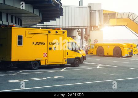 Start- und Landebahn service Fahrzeuge stehen auf Asphalt in der Nähe von airport terminal Building. Besondere Wartung crew Truck van und Schlepper an der gekennzeichneten Stelle geparkt Stockfoto