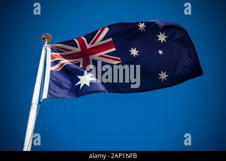 Australische Flagge im Wind fliegen gegen den klaren blauen Himmel Stockfoto