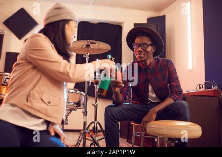 Portrait von Stattlichen afrikanischer Mann klirren Bierflaschen mit junge Frau beim Entspannen im Music Studio, kopieren Raum Stockfoto