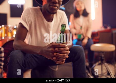 Im mittleren Abschnitt Portrait von trendigen afrikanischen Mann mit Bier Flasche beim Entspannen im Music Studio Stockfoto