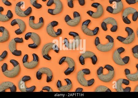 Hintergrundmuster aus hausgemachten Nougat Crescent Plätzchen mit Schokolade an den Rändern auf orangefarbenem Hintergrund Stockfoto