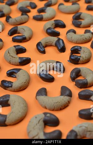 Hausgemachte Nougat Crescent Plätzchen mit Schokolade an den Rändern auf orangefarbenem Hintergrund Stockfoto