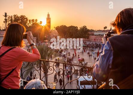 Touristen fotografieren Jemaa el-Fnaa bei Sonnenuntergang von der Terrasse Marrakesh-Safi in Marrakesch, Marokko. Stockfoto