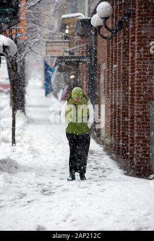 Miserable lone Einfrieren Frau entlang einer Straße der Stadt während eines Schneesturmes stapfen Stockfoto