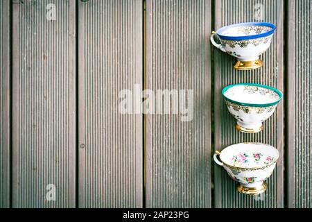 Set aus drei Vintage-Teebechern aus Porzellan mit Blumenschmuck auf Holzhintergrund mit Platz für Kopien Stockfoto