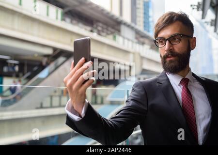 Die Jungen gut aussehenden bärtigen Persischen Geschäftsmann entspannende rund um die Stadt Stockfoto