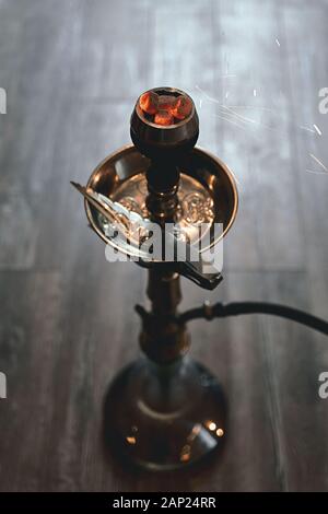 Shisha Hookah-Schüssel mit roten heißen Kohlen und Handtabak. Funken vom Atmen. Moderne Hookah mit Kokoskohle für Entspannung und Rauch. Wunderschön Stockfoto