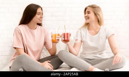 Zwei Freundinnen an jedem anderen suchen, lächelnd und Trinken frischen Smoothie Stockfoto