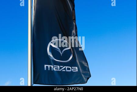 Dinslaken, Deutschland - Dezember 18. 2019: Isolierte logo Schriftzug Flagge der japanische Automobilhersteller Mazda gegen wolkenlosen blauen Himmel Stockfoto