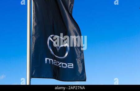 Dinslaken, Deutschland - Dezember 18. 2019: Isolierte logo Schriftzug Flagge der japanische Automobilhersteller Mazda gegen wolkenlosen blauen Himmel Stockfoto