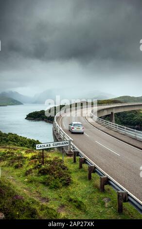 Auto fahren auf Kylesku Brücke über den Loch ein Chairn Bhain in Sutherland, Schottland, Teil der Nordküste 500 Scenic route Stockfoto