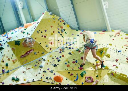 Free climber Kind junge Praktizierende auf künstliche Felsbrocken in der Turnhalle, Bouldern. Stockfoto
