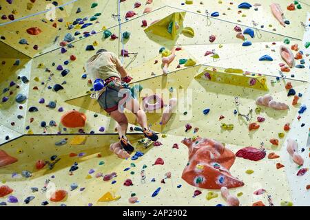 Free climber Kind junge Praktizierende auf künstliche Felsbrocken in der Turnhalle, Bouldern. Stockfoto