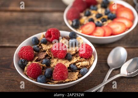 Müsli Chips mit Blaubeeren und Himbeeren in weiße Schüssel. Stockfoto