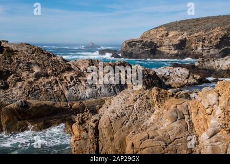 Blaue Winterwellen, die entlang der felsigen Pazifikküste des Point Lobos State Natural Reserve, Kalifornien, abstürzen Stockfoto