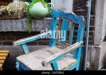 Blick auf isolierten alten retro Holzstuhl mit abblätternder Farbe und fensterbänke vor dem Haus Mauer Stockfoto
