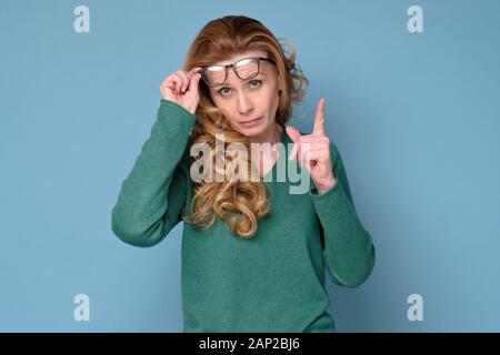 Schönen mittleren Alter reifen Business woman Brille zeigte mit dem Finger auf Rat geben. Studio shot Stockfoto