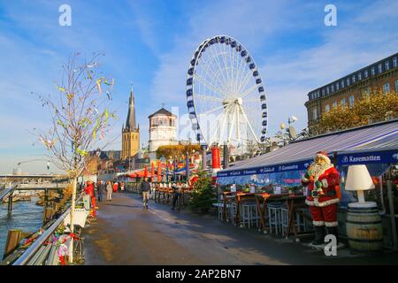 Düsseldorf, Deutschland - November 24. 2019: Blick über Fluss und Restaurants auf Weihnachtsmarkt Riesenrad von der Rheinpromenade Stockfoto