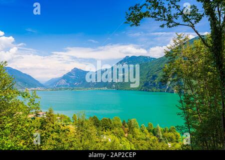 Schöner Blick über den Idrosee Italien. Häuser, ein kleines Dorf auf der Vorder- und blaues Wasser und Berge im Hintergrund. Stockfoto