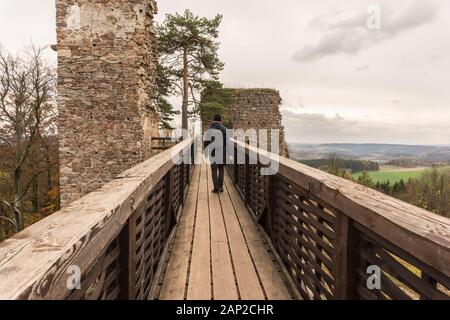Man touristische Fotograf holding Kamera gehen auf alte Holzbrücke im Herbst. Hölzerne Brücke und der alten Burg. Stockfoto