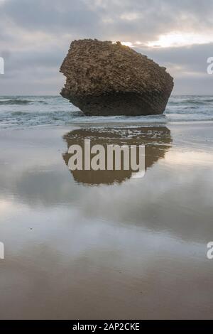 Der Felsen, Teil eines alten, auf dem Kopf stehenden Turms (Torre de la Higuera) am Strand in Matalascañas, Huelva, Spanien. Stockfoto