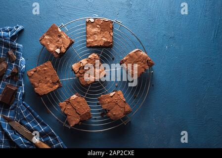 Chocolate brownies Quadrate auf eine Kühlung Fach, ein blaues Handtuch für die Küche, auf einem klassischen blauen Tabelle. Frisch gebackene Brownies. Beste fudgy brownies Kuchen. Stockfoto