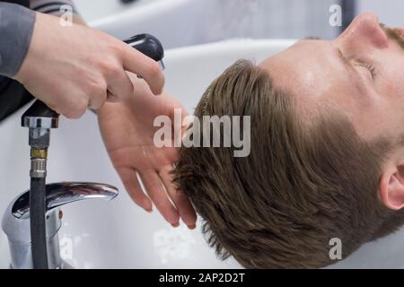 Nahaufnahme eines männlichen Hair Care Master, wäscht ein mans Kopf in ein Waschbecken nach dem Schneiden die Haare. Professionelle männlichen Haarpflege im barbershop. Stockfoto