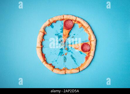 Pizza Salami letzte zwei Scheiben und Pizza crust Reste auf blauem Hintergrund. Oben Ansicht von Kruste und Pizza Pizza Salami Schnitte. Fast food. Stockfoto