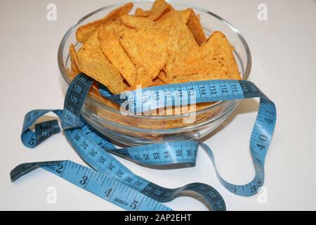 Chips in eine Schüssel und Meter als Konzept des Seins nicht gesund Stockfoto