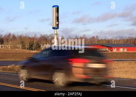 Auto vorbei an einem modernen Straßenrand Blitzer in Höchstgeschwindigkeit auf einem sonnigen Tag des Winters. Lange Belichtung das Fahrzeug zu verwischen. Stockfoto