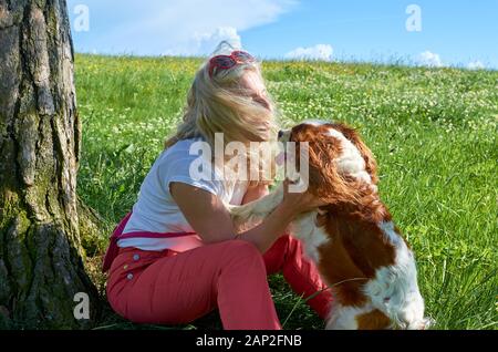 Frau genießen einen Moment mit Ihrem kleinen Cavalier King Charles Spaniel outdoor im Frühjahr Stockfoto