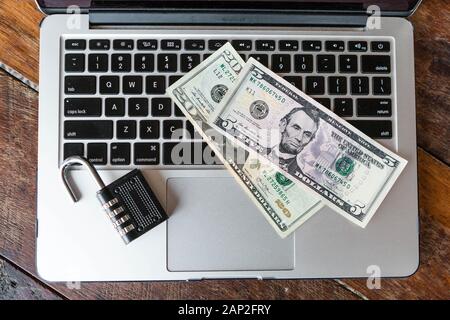 Blick von oben auf ein Vorhängeschloss und amerikanische Dollar auf einem Laptop. Online Security Konzept, Online-Banking, Anti Virus Stockfoto