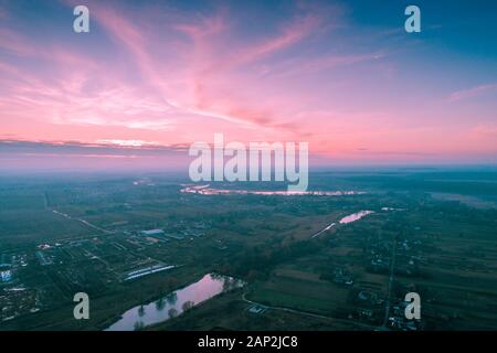 Magischen Sonnenuntergang in der Landschaft im Herbst. Ländliche Landschaft am Abend. Luftaufnahme von Bach-, Dorf- und Ackerflächen. Panoramablick. Panorama Stockfoto