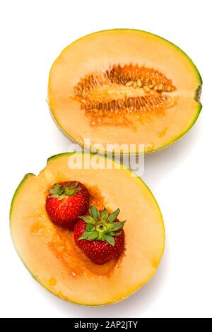 Melone Hälften mit und ohne Samen, auf weissem Hintergrund - Zwei frische Erdbeeren in einer Melone Hälfte. Stockfoto