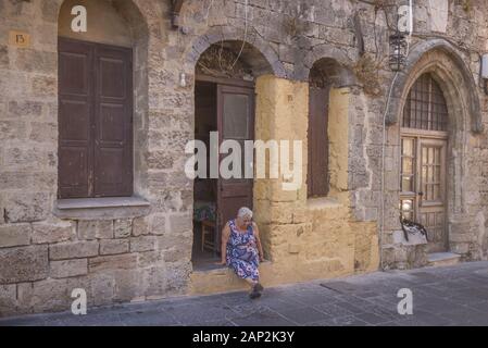 August 8, 2018, Rhodes, Griechenland: Eine ältere Frau sitzt auf der Treppe ihres Hauses. Stadtbild in der mittelalterlichen Stadt innerhalb der Befestigungsanlagen von Rhodos. (Bild: © Andrey Nekrasov/ZUMA Draht) Stockfoto