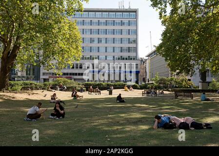 Leute sitzen auf Gras und Essen in Cavendish Square, Marylebone, Westminster, London England Großbritannien UK Stockfoto