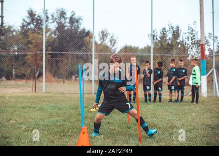 Fußball-Bohrer: Der Slalom Bohren. Jugend-fußball-Übungen. Jungen Fußball-Training der Tonhöhe. Fußball slalom Konus bohren. Junge in Fußball jerse Stockfoto