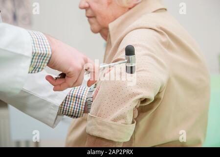 Orthopädischer Chirurg Prüfung der Knie Reflex. Der Arzt prüft die physiologische Reflex, der Test Hammer. Arzt Reflexe prüfen Stockfoto