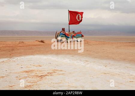 Die Flagge am Chot El Jerid Salt Lake Rest. Die Berge im Hintergrund. Stockfoto