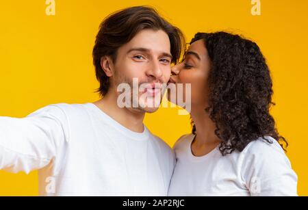 Liebende schwarze Freundin küssen Ihres Freundes Wange während der Einnahme von selfie Stockfoto