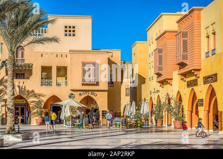 Spielende Kinder und Eltern reden amomg bunten ägyptischen Häuser an der Piazza Marina in El Gouna, Ägypten, 11. Januar 2020 Stockfoto