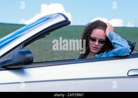 Eine traurige oder nachdenkliche Frau sitzt auf dem Fahrersitz eines wandelbaren Automobil Stockfoto