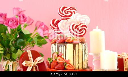 Valentinstag auf - Tendenz candyland Fantasy drip Neuheit Kuchen mit herzförmige Lollis, Candy und frische Erdbeeren dekoriert. Close Up. Stockfoto