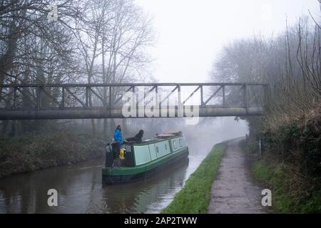 Frau mit zwei Hunden, die das schmale Boot auf Trent und Mersey Kanal in der Nähe von Stoke on Trent, Großbritannien steuern. Stockfoto